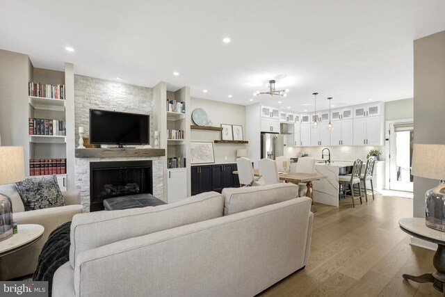 living room with recessed lighting, a fireplace, light wood-type flooring, and an inviting chandelier