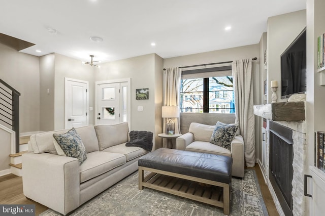 living area with wood finished floors, baseboards, recessed lighting, a fireplace, and stairs