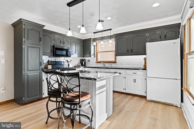 kitchen featuring light wood finished floors, stainless steel electric range, freestanding refrigerator, decorative backsplash, and black microwave