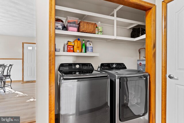 washroom with washer and dryer, laundry area, and wood finished floors