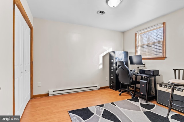 office space with visible vents, a baseboard heating unit, baseboards, and wood finished floors