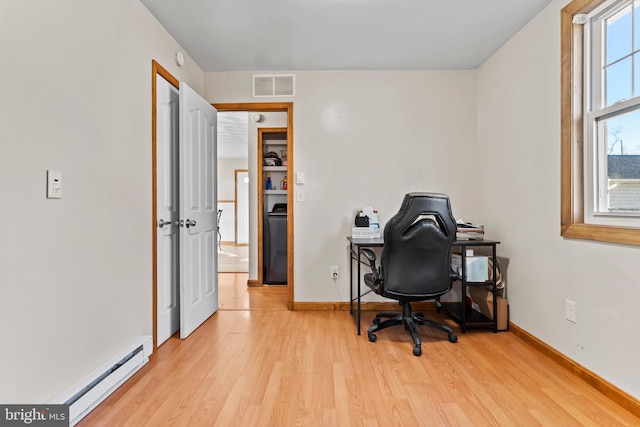 office with visible vents, light wood-style flooring, a baseboard heating unit, and baseboards