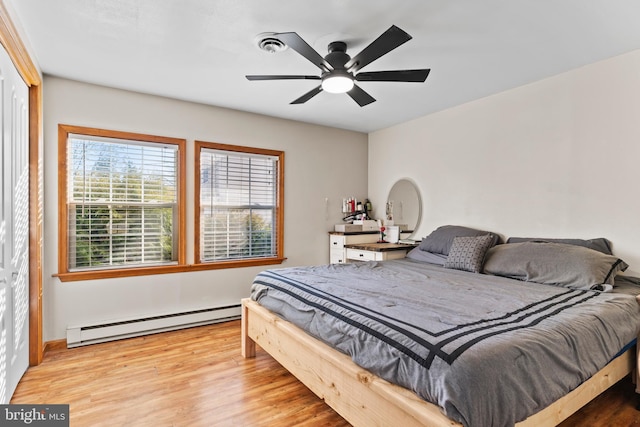 bedroom with a baseboard heating unit, wood finished floors, and a ceiling fan