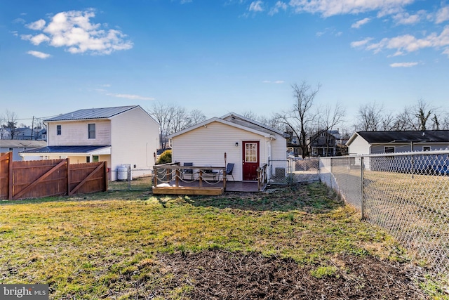 rear view of house with a yard, a fenced backyard, a deck, and a gate