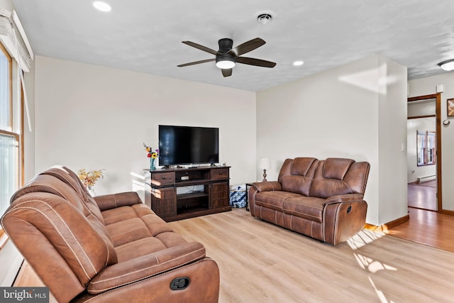 living area with a baseboard heating unit, wood finished floors, visible vents, and ceiling fan