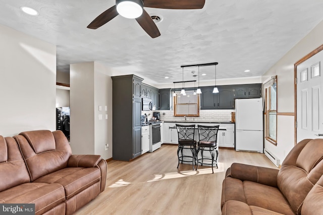 living area featuring visible vents, a baseboard heating unit, recessed lighting, light wood-style floors, and ceiling fan