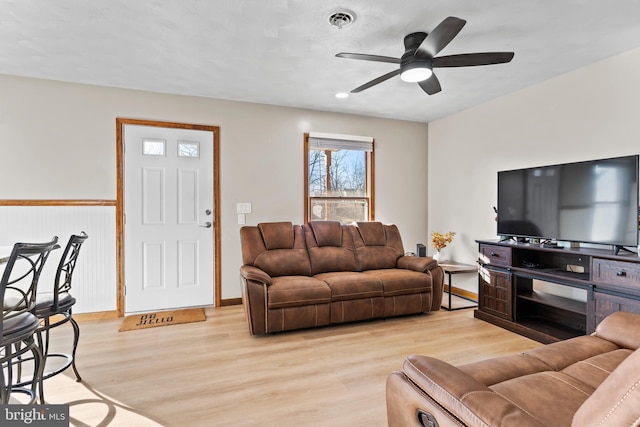 living area with visible vents, a ceiling fan, light wood-type flooring, and baseboards