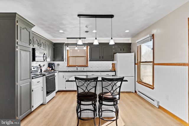 kitchen featuring electric stove, a sink, dark countertops, freestanding refrigerator, and a baseboard radiator