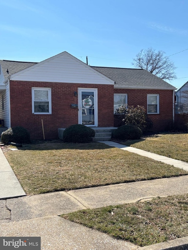 ranch-style home with brick siding, a shingled roof, and a front lawn