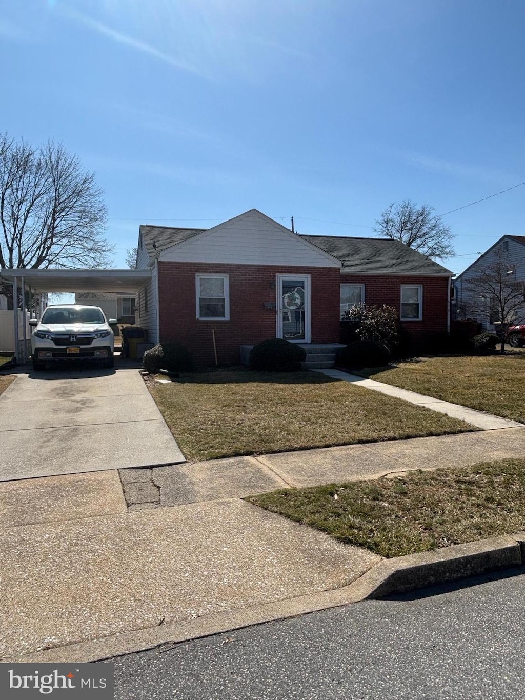 view of front of property with brick siding, concrete driveway, and a front lawn