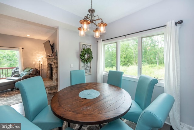 dining area featuring a stone fireplace and an inviting chandelier