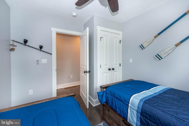 bedroom with wood finished floors, visible vents, ceiling fan, a closet, and a textured ceiling