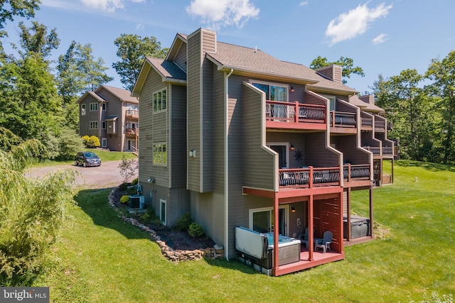 rear view of property with a lawn, a chimney, and central AC