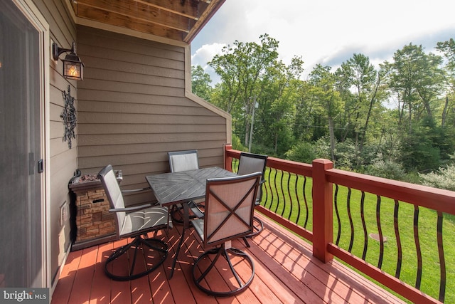 wooden deck with outdoor dining space and a yard