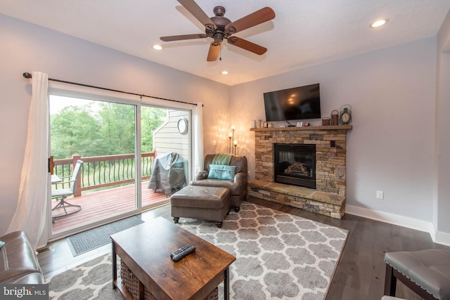 living area featuring a ceiling fan, wood finished floors, recessed lighting, a stone fireplace, and baseboards