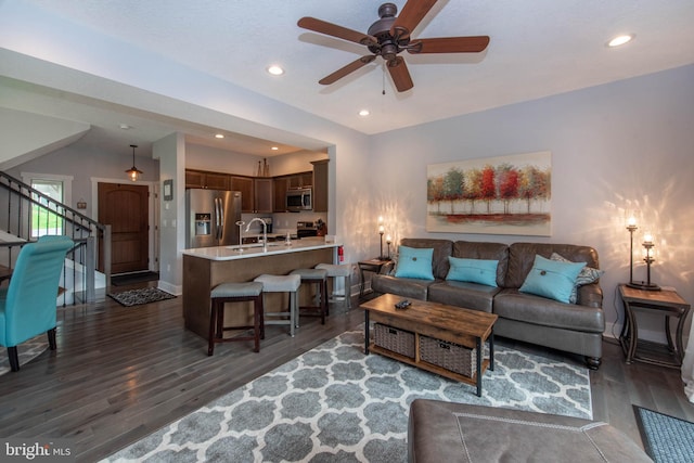 living area with recessed lighting, baseboards, dark wood-type flooring, and stairs