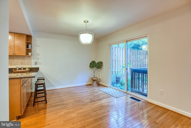 unfurnished dining area with light wood-type flooring, baseboards, and visible vents