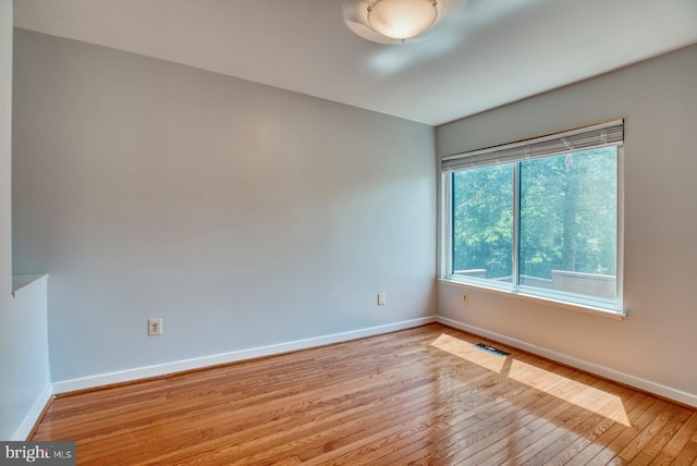 empty room featuring visible vents, baseboards, and hardwood / wood-style flooring