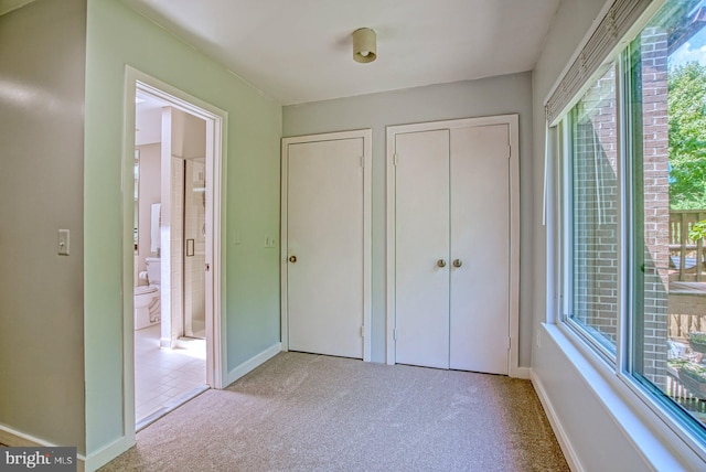 unfurnished bedroom with ensuite bath, baseboards, and carpet floors