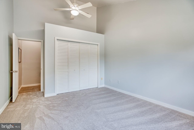 unfurnished bedroom featuring a closet, baseboards, carpet, and high vaulted ceiling