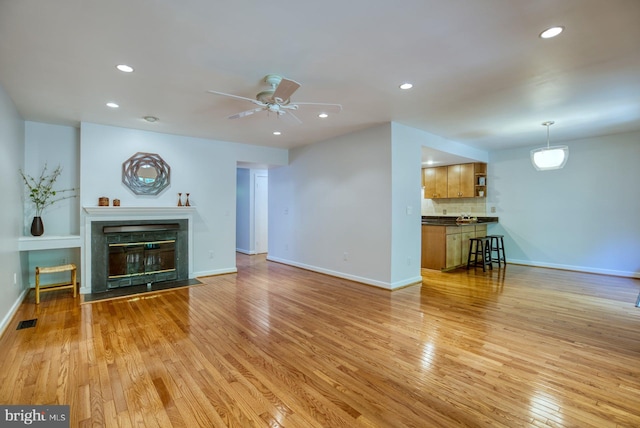 unfurnished living room featuring visible vents, baseboards, a fireplace with flush hearth, recessed lighting, and light wood-style floors