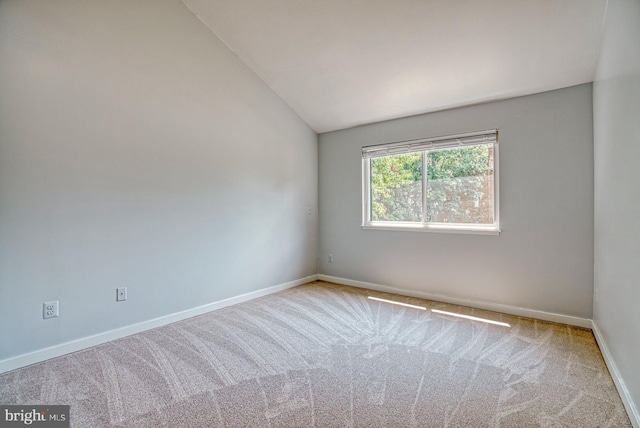 empty room featuring carpet flooring, lofted ceiling, and baseboards