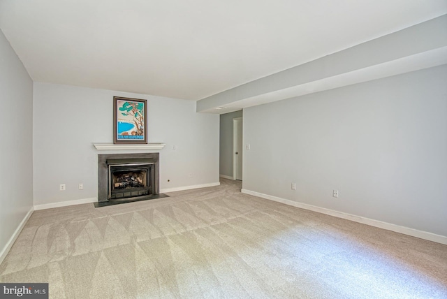 unfurnished living room with baseboards, a fireplace with flush hearth, and light colored carpet