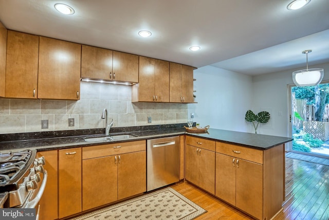 kitchen featuring a peninsula, light wood-style flooring, a sink, stainless steel appliances, and tasteful backsplash