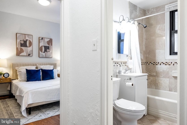 ensuite bathroom featuring shower / bathtub combination with curtain, toilet, a sink, connected bathroom, and a textured wall