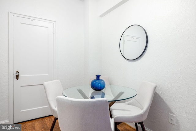 dining area with a textured wall and wood finished floors