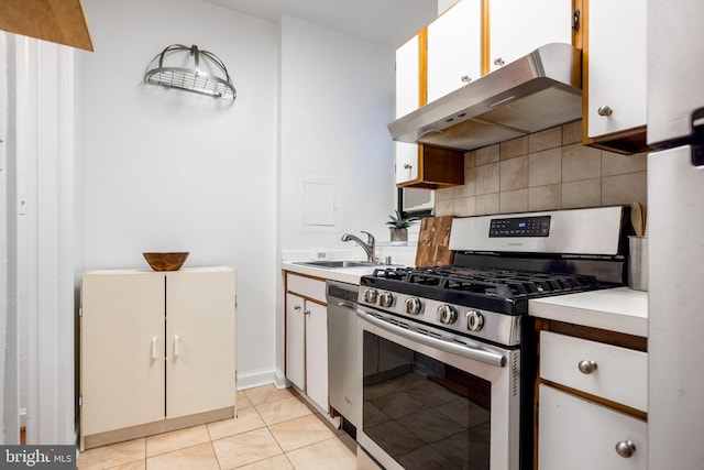 kitchen featuring a sink, light countertops, under cabinet range hood, appliances with stainless steel finishes, and backsplash