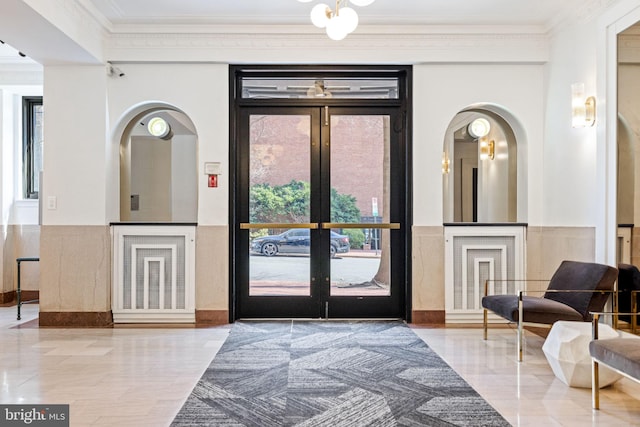 interior space with french doors, arched walkways, and crown molding