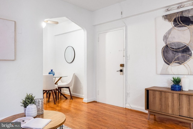 entrance foyer featuring arched walkways, baseboards, and wood finished floors