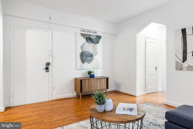 interior space with baseboards, arched walkways, and light wood-type flooring