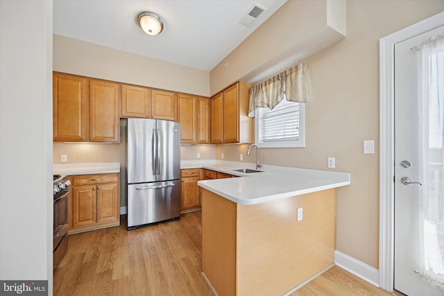 kitchen featuring a sink, light countertops, light wood-type flooring, and stainless steel appliances