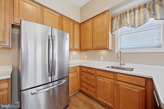 kitchen featuring light countertops, freestanding refrigerator, and a sink