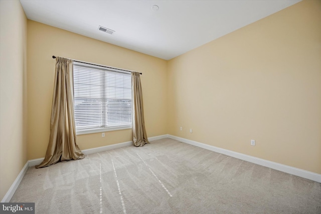 empty room with carpet, visible vents, and baseboards