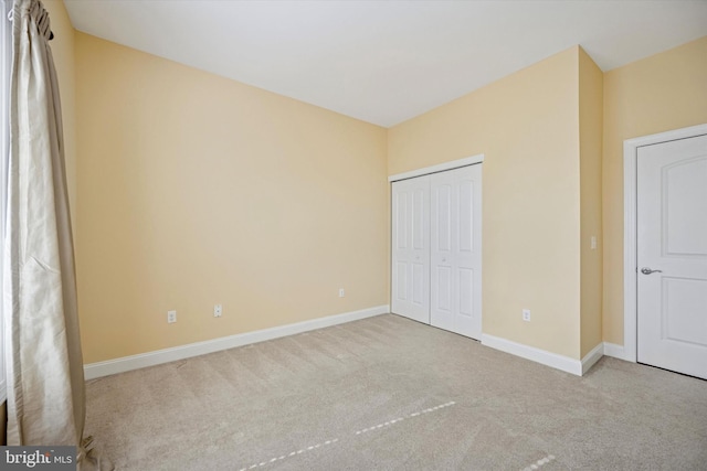 unfurnished bedroom with baseboards, carpet floors, and a closet