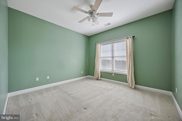 carpeted spare room featuring visible vents, baseboards, and a ceiling fan