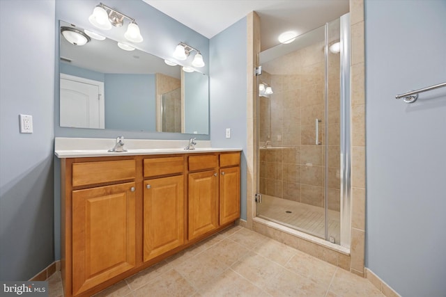 bathroom featuring a shower stall, double vanity, tile patterned floors, and a sink