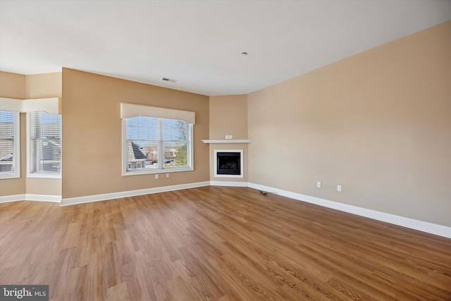 unfurnished living room featuring visible vents, light wood-style flooring, a fireplace, and baseboards