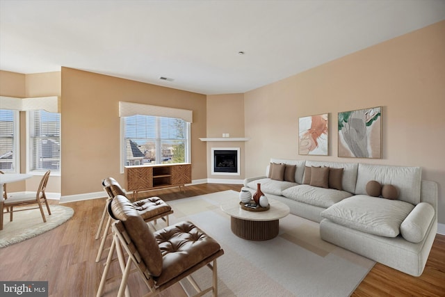 living area with visible vents, a fireplace, baseboards, and wood finished floors