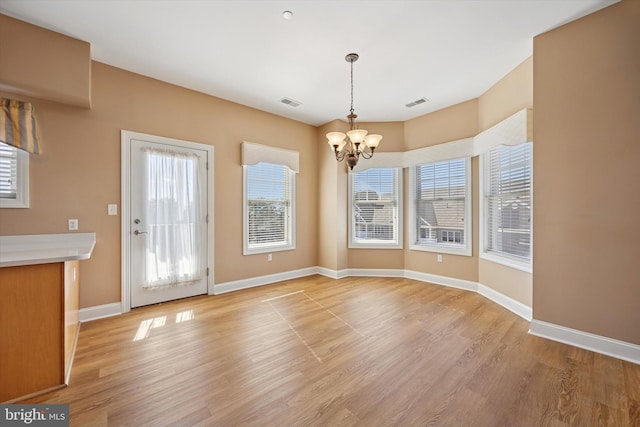 unfurnished dining area with visible vents, baseboards, a chandelier, and light wood finished floors