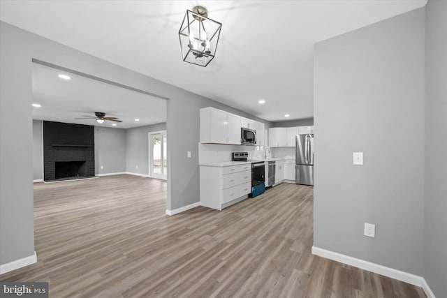 kitchen with baseboards, light wood-type flooring, light countertops, white cabinets, and stainless steel appliances