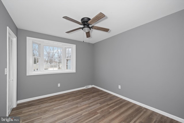 unfurnished bedroom featuring wood finished floors, visible vents, baseboards, ceiling fan, and a closet