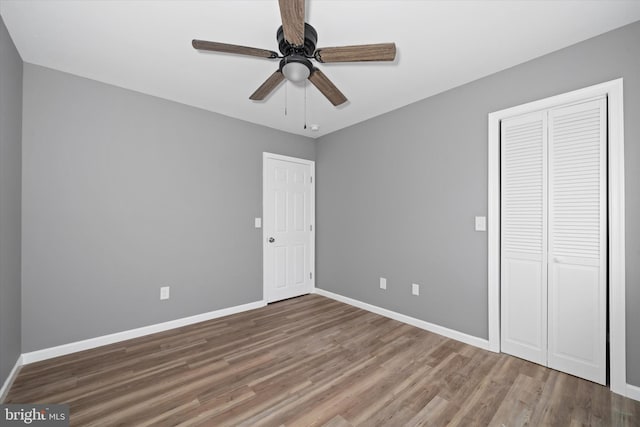 unfurnished bedroom with a closet, a ceiling fan, baseboards, and wood finished floors