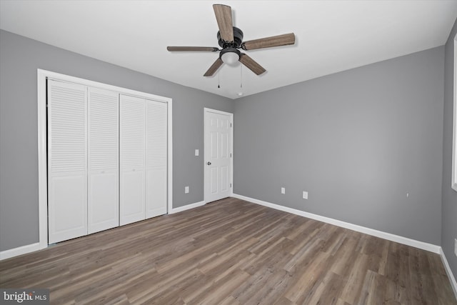 unfurnished bedroom featuring a closet, baseboards, wood finished floors, and a ceiling fan