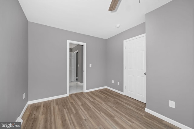 unfurnished bedroom with ceiling fan, baseboards, and wood finished floors