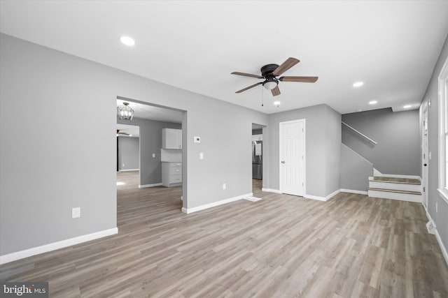 unfurnished living room featuring light wood-style flooring, baseboards, and ceiling fan