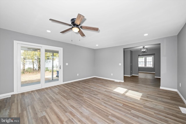 unfurnished living room with recessed lighting, baseboards, wood finished floors, and ceiling fan with notable chandelier